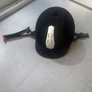 Ridhjälm CRW - Endast använts en kort tid sedan sluta hon med ridning. Inköp ny av oss! Ridhjälm, klädd med microfibermocka. Justerbar i storlek, vilket gör att du får en perfekt passform. M: 56-58. Ventilation fram och bak.mjuk skärm för minskad skaderisk.