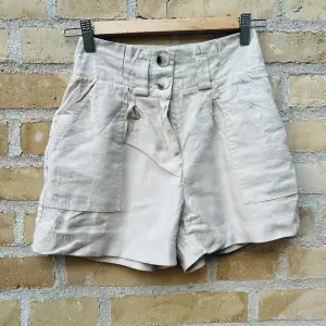 Snygga beige shorts med hög midja och lite lösare nertill. Fickor. Knappt använda. Från Amisu. Mätt rakt över midjan: 34 cm. Längd mitt på benet bak: 37 cm. Materialet är viskos 93 % och resten polyester.