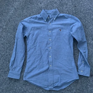 Ljusblå Ralph Lauren Skjorta - Hej! Säljer nu denna skjortan då den har blivit för liten för mig. Storlek: Xs smal Passform: Slim fit Material:  Bomull Skick: 9/10 väldigt bra skick, inga märken eller slitage  Nypris: 1400 kr  Hör gärna av dig vid eventuella frågor och funderingar