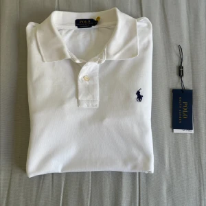 Vit pikétröja från Polo Ralph Lauren - En klassisk vit pikétröja från Polo Ralph Lauren med en broderad logotyp i mörkblått på bröstet. Tröjan är aldrig använd då den var för stor för mig. Storlek S, men skulle säga att den passar S - M. Inköpt på care of carl för 1299, och säljs nu för 899. Vid frågor kontakta gärna, kan även gå ner i pris vid snabbaffär. Vid frågor kontakta gärna. 