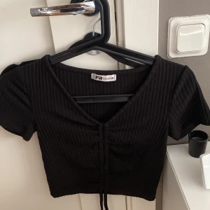 Svart tshirt FB sisters - Tshirt från FB sisters i strl xxs men töjbar så passar även xs Band i mitten av tröjan som kan knytas beroende på hur man vill att den ska sitta Pris kan diskuteras Bra skick och tvättas även innan den skickas💗