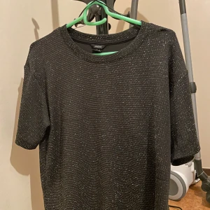 Glittrig blus. - En fin festlig blus från Lindex, i storlek xs. Ganska skön material. Aldrig använt den, för lite för mig. 
