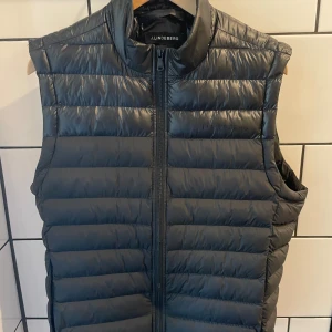 J.Lindeberg dunväst  - J.Lindeberg dunväst i nyskick, använd väldigt fåtal gånger.  Köpt för 1800 kr på J.Lindebergs hemsida.  Storlek L men passar även M.  Hör av er vid funderingar! 