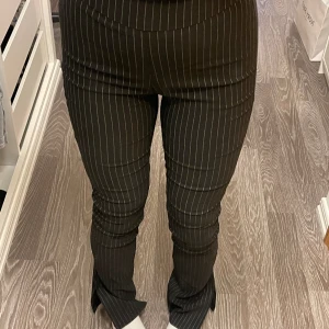 Randiga kostymbyxor - Tighta randiga och högmidjade kostymbyxor med slits nedtill. Passar mig som är 167cm lång. Storlek 38.