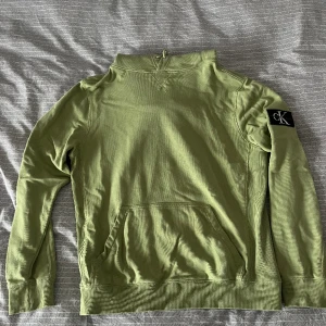 Calvin Klein Hoodie - Ljusgrön Calvin Klein Hoodie med fastsydd patch med logga på ärmen. En aning oversized.  Nypris: 1099kr  Skick: Bra, använd några gånger, inga synliga brister  Säljs för att den inte passar mig