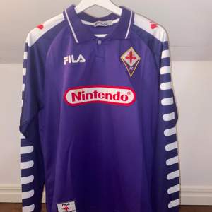 Säljer denna Fiorentina tröja med långa ärmar. Använd en gång och har bara en liten fläck på sponsorn. Tvättas innan den skickas. Pris kan diskuteras 