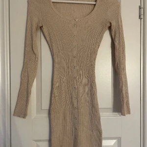 Tajt klänning  - Beige tajt klänning, silver knappar, ribbad, från NEW YORKER i storlek xss. Jätte fin klänning och är i bra skick.  