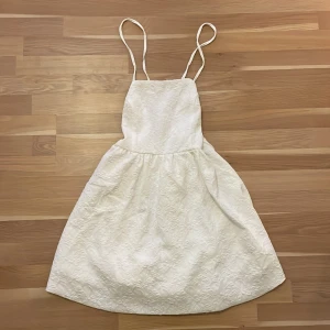  Vit blommig studentklänning  - Vit blommig studentklänning i storlek L (men passar även mindre). Aldrig använd.