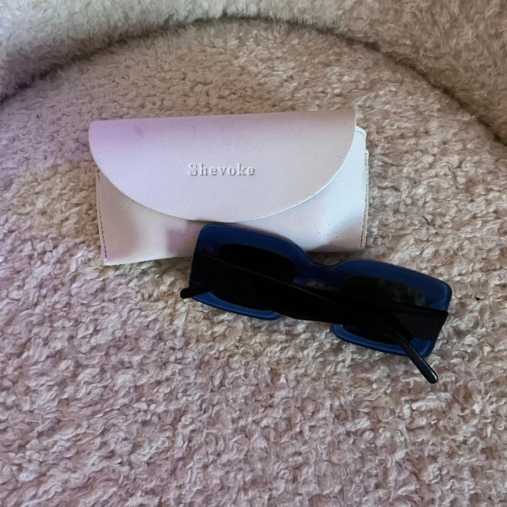 Säljer ett par fina solglasögon från australiensiska märket Shevoke, modell MK ZINGARO NOIR.  Glasögonen är tvåfärgade, svarta utanpå och blå på insidan.  Mått: Lins höjd 35 mm,  lins bredd 45 mm, längd 140 mm. Accessoarer.