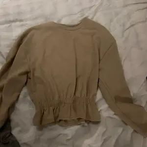 En beige blus från ginatricot med en volang nertill! Storlek xs men passar s och m också!