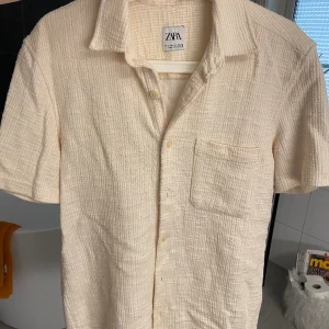 Kortärmad skjorta - En jättesnygg kortärmad skjorta från Zara i storlek S. Har ett fint tyg/mönster i cremevit färg. Som nyskick, köparen står för frakt.