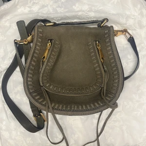 Rebecca Minkoff väska  - Superfin väska i 100% läder, mocka liknande läder. Därav färgskiftningar. Många fina detaljer. Färgen är mossgrön. Avtagbart axelband och extra snören. 3 fack inuti och ett på utsidan.  Höjd 20 Bredd 23