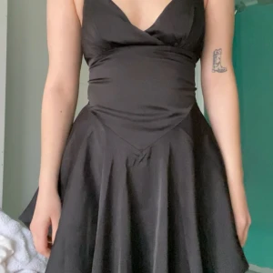 Svart klänning - Svart klänning i satin storlek XS med knytning i ryggen