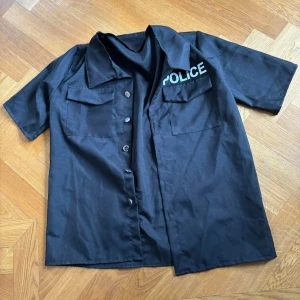 "polisskjorta" i svart och vitt - En skjorta i syntetiskt material från en polisutklädnad.