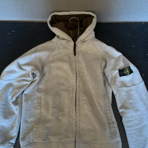 Stone Island Hoodie. - Säljer nu denna feta Vit/gråa stone island hoodien i storleken "Junior" Som passar någon runt 170 cm. Den är i ganska gott skick utan hål. Hör av dig vid frågor. Självklart äkta annars får du pengarna tillbaka. Vill få bort den ASAP därav priset.