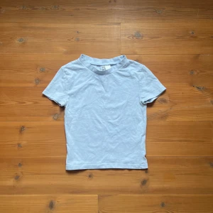 kort topp - Kort, tajt t-shirt i en klar ljusblå färg. Fint skick och i princip helt oanvänd. Mjukt material och tajt!