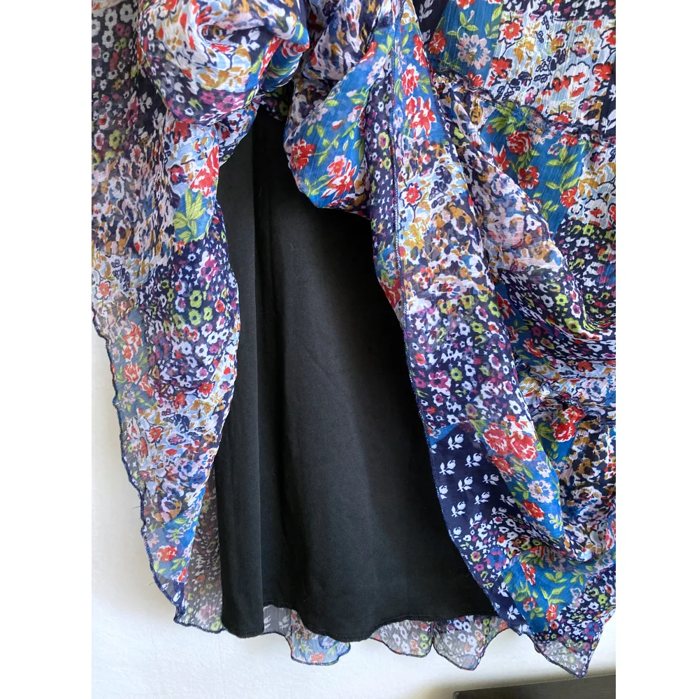 Blå blommig kjol i chiffong med volanger, bred elastisk linning. Mått i cm: midjevidd 36; längd 91.. Kjolar.