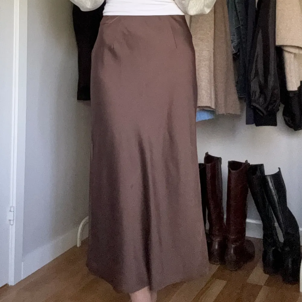 En brun midikjol i satin. Kjolen kommer ifrån Bikbok och är knappt använd, köpt förra året. Har en liten slits vid ena sidan. Längden på den är 90cm.. Kjolar.