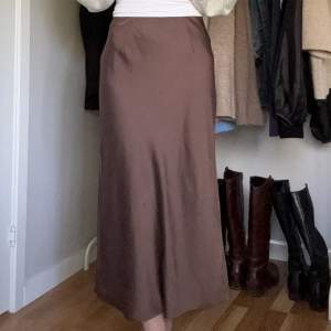 En brun midikjol i satin. Kjolen kommer ifrån Bikbok och är knappt använd, köpt förra året. Har en liten slits vid ena sidan. Längden på den är 90cm.