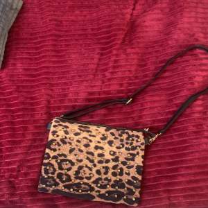 En skitsnygg leopardmönstrad axelväska med justerbart band. Väskan har gulddetaljer samt gjord av läder och mjukt tyg. Köpt för 300kr