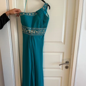 Balklänning - Blå balklänning med strassdetaljer. One shoulder i storlek 10, passar en 36a. Endast använd 1 gång.