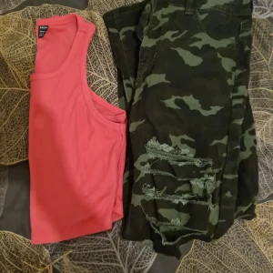Helt nya camouflage jeans+top stlM shein - Helt. Nya. Camouflage jeans med hål på framsidan av benen dom är tillverkade så stl M (38) samt ett nytt  linne kort stl M (38) båda från shein 