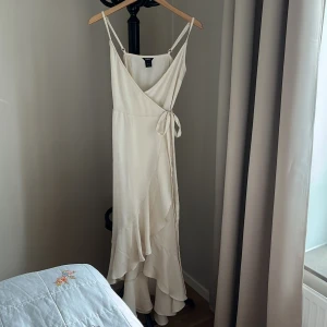 Klänning i omlott - Superfin pärlfärgad klänning köpt på Lindex. Storleken är XS men skulle säga att den även passar S. Justerbara, tunna axelband och omlott midja. Aldrig använd då den är för lång på mig (155cm), nyskick!