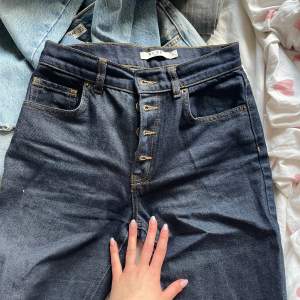 mörkblå NAKD jeans med snygga knappar och utsvänga med slits. De är i storlek 34 men skulle säga att de är större typ 36-38 
