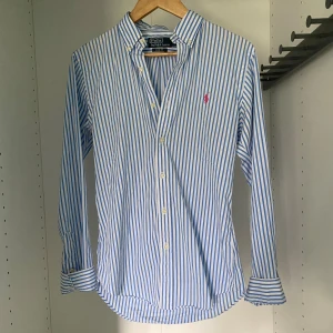 Ralph Lauren skjorta - Somrig rl skjorta i slim fit modell. Hittade en väldigt liten fläck (bild 4) men har aldrig märkt den innan. Användes förra sommaren och är nu för liten. Passar tts så någon som vanligtvis har strl S.