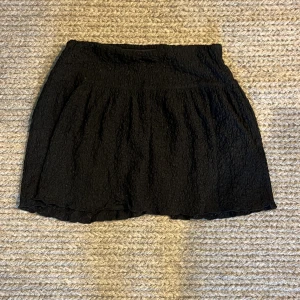 Kjol  - Svart kjol ifrån Gina Tricot med struktur. Den är storlek S och lågmidjad. Knappt använd.