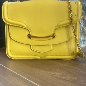 Alexander Mqueen Heroine Chic Leather Bag - 28 cm bred, 22 cm hög.  En äkta ALEXANDER MCQUEEN Calfskin Heroine Chain Satchel i Citrongul färg. Denna snygga shoulder bag är gjord i kalvskinns läder i gult. Guld länk shoulder strap och läder shoulder pad.  Köpt på Vestaire i Maj. Fläckar,se bild