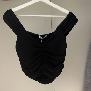 Svart topp - En svart topp från zara med srunsch i mitten av toppen. Aldrig använd, prislappen kvar. Storlek M. 