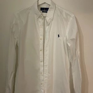Polo Ralph Lauren - Slim Cotton - Polo Ralph Lauren - Skjorta / Shirt - Slim Cotton  Jag säljer min Polo Ralph Lauren-skjorta 100% original och i perfekt skick. Storlek: S Färg: White / Gray Material: Cotton 100% Skick: Mycket Bra Sex: Man