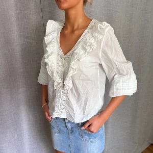 Blus med volanger - Så söt blus med fina detaljer, går att ha på två sätt med armarna som man ser på bilderna. Har en liten kaffefläck på ärmen som jag inte tycker man tänker på. Storlek 34 men passar större också. Behöver strykas