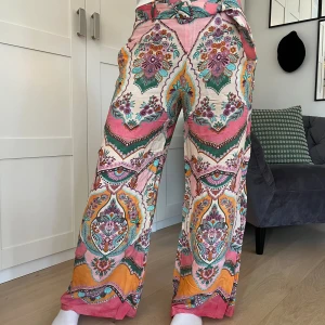 Mönstrade byxor - Mönstrade, färgglada byxor från Zara med skärp i midjan. Lite små i storleken.