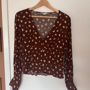 Blommig blus  - Fin brun, blommig blus i nyskick från Monki. Knäppning över magen och luftiga ärmar. Endast använd ett par få gånger 🌷 Stl M 🌷