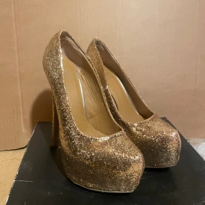 Guld glittriga klackskor  - Glittriga Guld klackskor.  Högklack, endast testade. Storlek 38