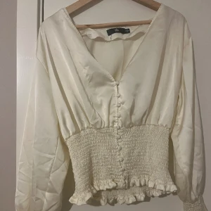 Beige blus i satin - Säljer min eleganta satinblus i beige. Bara använt en gång.