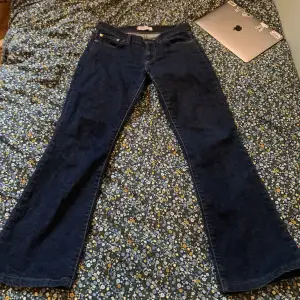 Ett par mörkblå bootcut Levi’s jeans med låg midja. Storlek S. Midjemått tvärsöver är 39. 