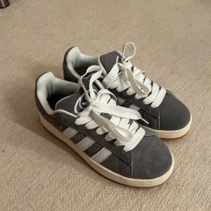 Adidas campus 00 - Säljer ett par helt oanvända adidas campus 00 gråa i storlek 39 1/3 . Köpta på Plick men säljs vidare pga för små i storlek. 