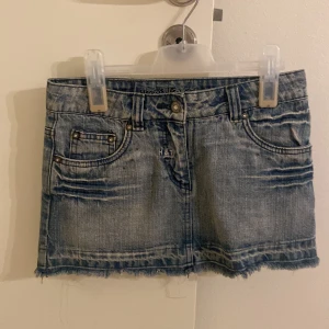 Jeanskjol från Here+There med vågdetalj - XXS som passar ändå som XS. Snygg ljusblå jeanskjol från Here+There med rå kant nertill och coola blå vågdetaljer på bakfickorna. Klassisk femficksmodell med slitningar och bälteshällor. Perfekt för dig som gillar en avslappnad och trendig stil.