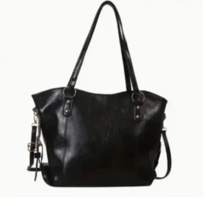 Svart axelväska i skinn - Stilren svart axelväska i skinn med långa handtag och avtagbar axelrem. Väskan har en klassisk form och metallspännen i silverfärg. Perfekt för att bära allt du behöver till skolan eller stan.