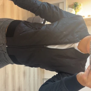 Svart quiltad bomberjacka Vero Moda - Snygg svart bomberjacka från Vero Moda med quiltat mönster och dragkedja framtill. Jackan har ribbade muddar vid ärmslut och midja, samt två fickor med dragkedja. Perfekt för dig som gillar en stilren och urban look.