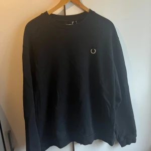 Svart sweatshirt Raf Simons x Fred Perry XL - Svart sweatshirt från Raf Simons x Fred Perry i storlek XL. Klassisk design med broderad Fred Perry-logga på bröstet. Tröjan sitter fett skönt och är i bra skick! Ny pris 1800kr. Dm mig för att diskutera priset:) 