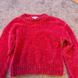 Rosa stickad tröja  - Mysig mörk rosa tröja i mjuk manchester med bred ribbad kant vid hals, ärmslut och nederkant. 