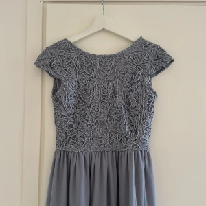 Lång grå/blå klänning - Långklänning i grått med spets och korta ärmar.