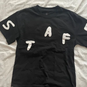 Astroworld svart t-shirt Travis Scott - Svart Astroworld Festival t-shirt från Travis Scott med stora vita 3D-tryckta bokstäver fram och bak. T-shirten är i 100% bomull och har cool festivalgrafik med Houston, TX och 2019 på ryggen. Perfekt för dig som gillar streetwear och unika prints.