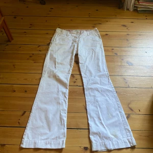 Vita byxor  - Vita lågmidjade utsvängda byxor med söta fickor. Innerbenslängd: 81. Midja 40. 