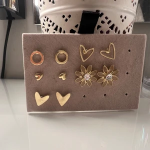 Set med guldiga örhängen i olika former - 190kr per styck par!!!! Skriv vilken. Flera par örhängen i guldton, bland annat hjärtformade, blommor med glittrande stenar och enkla ringar. Perfekt för dig som vill mixa och matcha olika stilar. Alla örhängen är små och i metall med snygg finish.