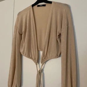 Beige omlottkofta från BikBok XS - går knyta på olika sätt, hålen bak är att rekommendera, men går utan att trä igenom dem också. Bra skick!
